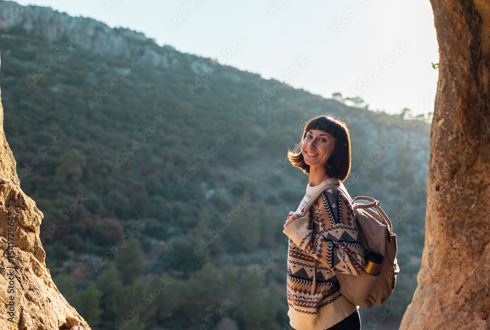 Naklejka premium Portrait of happy female tourist in mountains. girl smiles. trekking and hiking. girl with backpack.