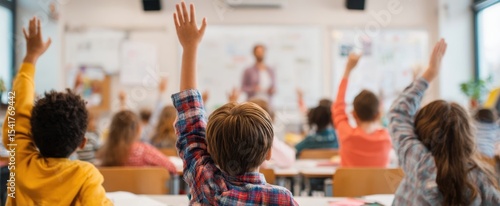 The eager children raising hands in a bright classroom during engaging lesson.