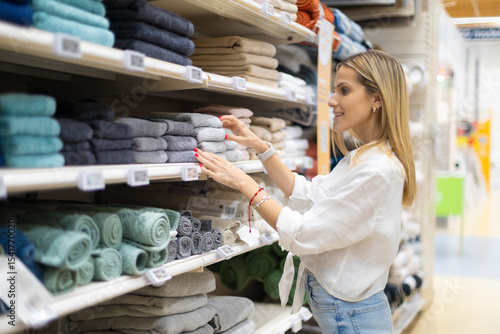 Woman choosing towels in supermarket household goods department