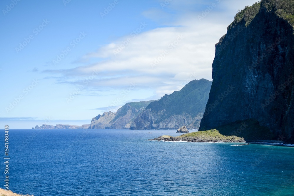 Naklejka premium Steep ocean cliffs and coastal mountains under blue sky