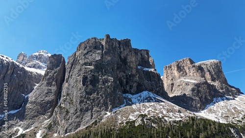 Steep mountain with snow on top and trees beneath. Photograph taken in the dolomites, italy in 4K with a drone. 