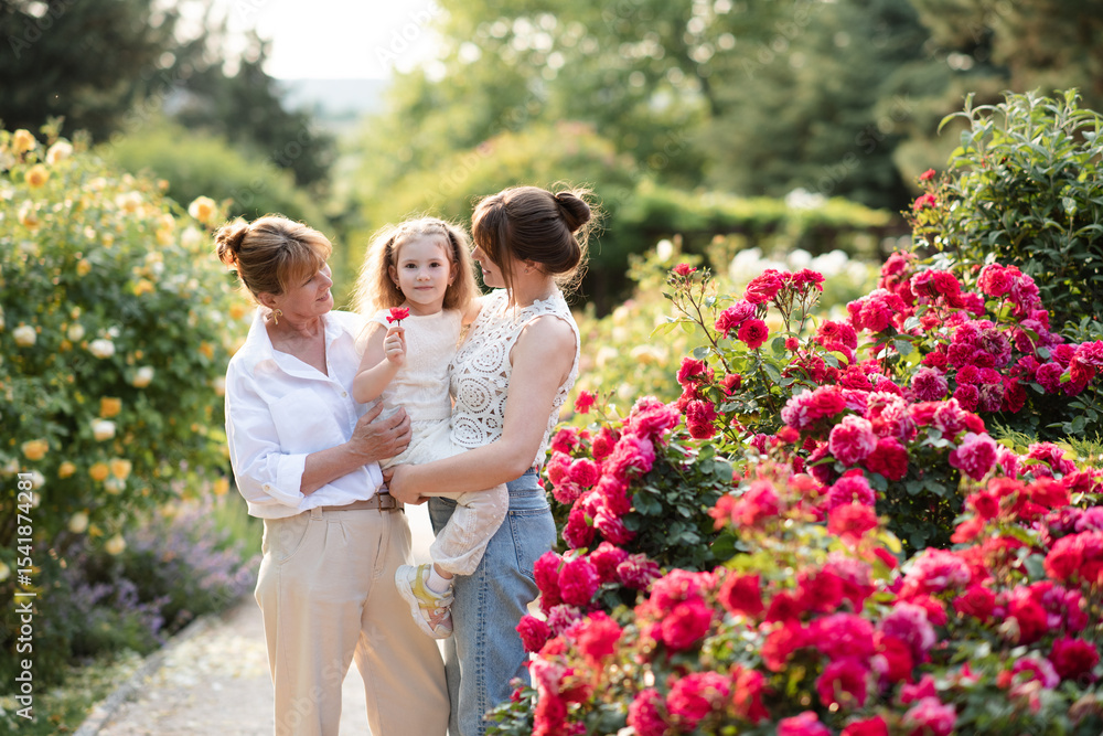 Child girl 4-5 year old with mother and granny in garden with flowers outdoors. Motherhood. Summer season. Child girl 4-5 year old with mother and granny in garden with flowers outdoors. Motherhood. Summer season.