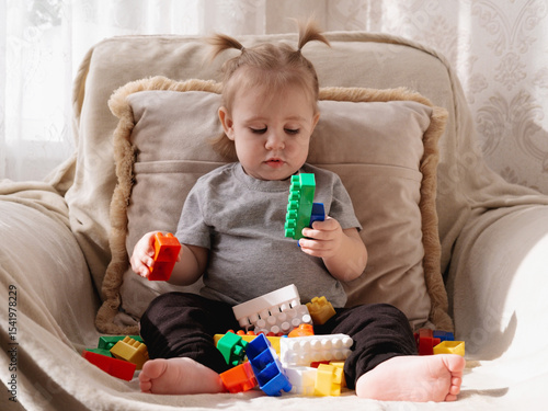 Little toddler sits with colorful building blocks but shows no emotional engagement, highlighting early signs of possible autism