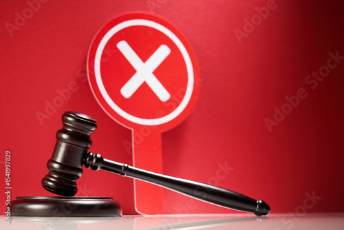 wooden gavel and cross mark on red background.