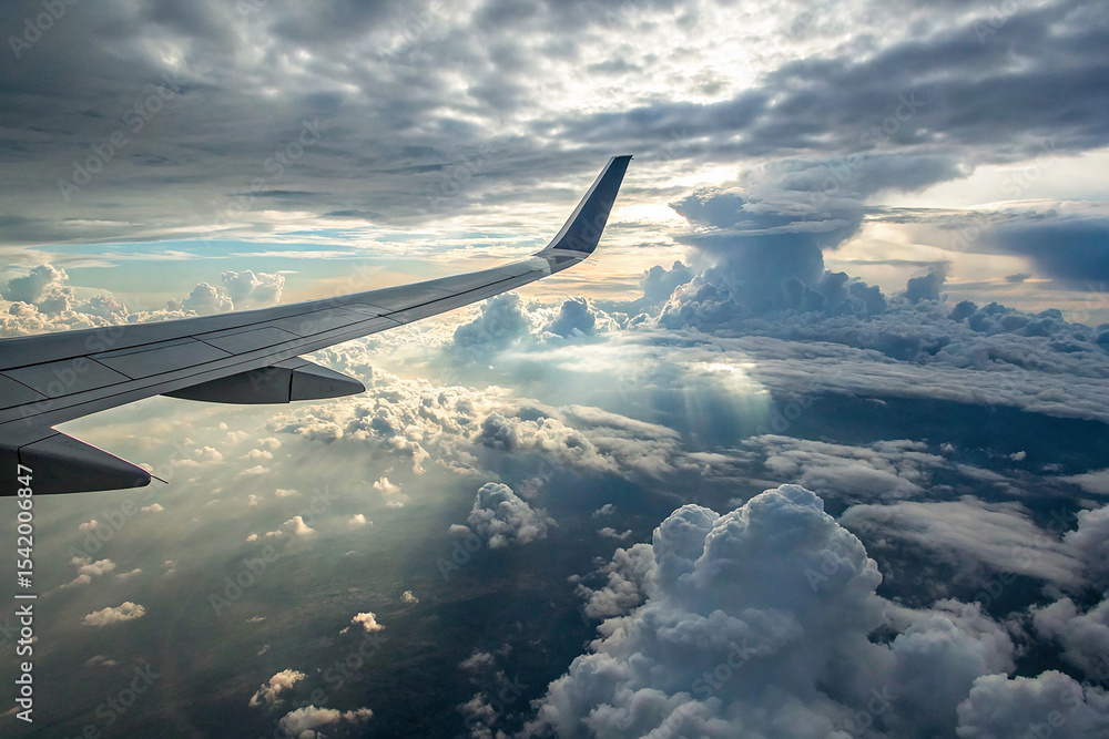 Obraz premium A plane wing cuts through a cloudy sky, offering a glimpse of the vastness of the atmosphere.