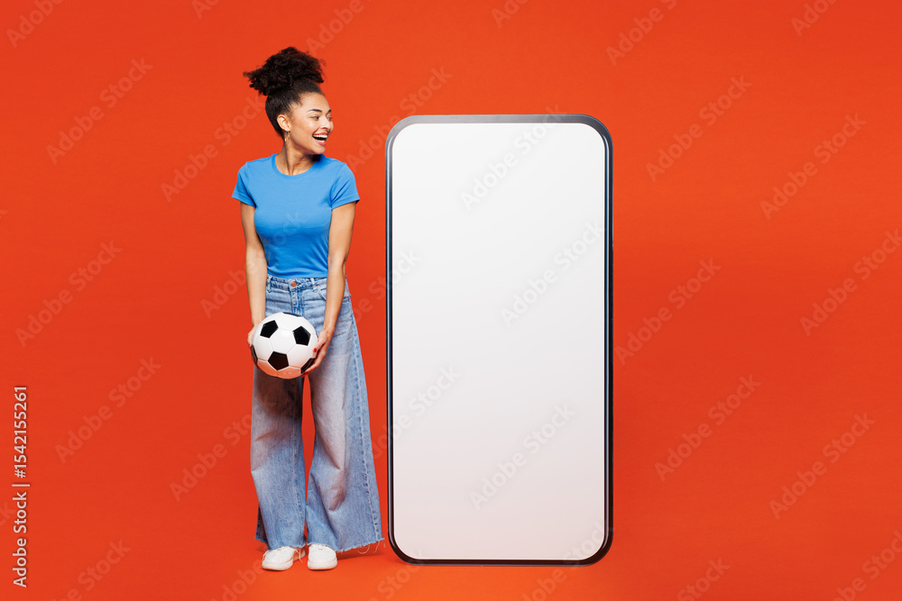 Φωτογραφία Full body young woman fan in blue clothes cheer up support football sport team hold soccer ball watch tv live stream look at big blank screen mobile cell phone isolated on plain red orange background
