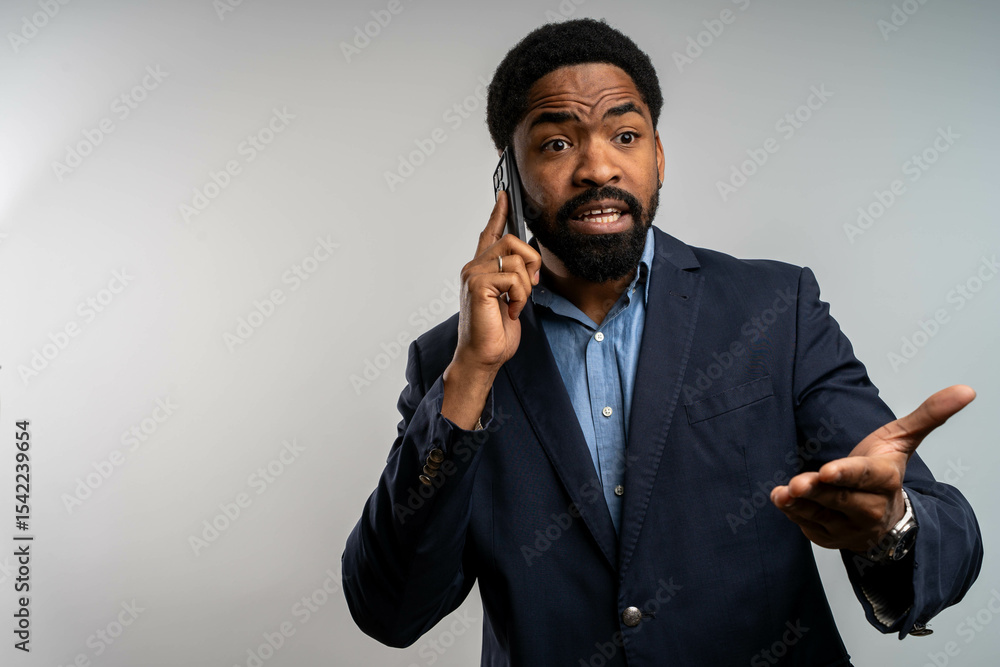 Naklejka premium Confused Black businessman talking on phone, seeking explanation, isolated on white background