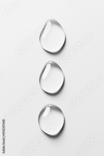 Water droplets cascade gracefully in a vertical line on a white surface, showcasing their clarity and forms