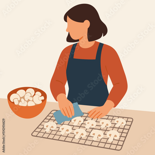 Woman preparing mushrooms in kitchen while wearing apron  