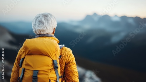 An elderly hiker in a bright yellow jacket stands in awe of a breathtaking mountain landscape, embodying the spirit of adventure and legacy in outdoor exploration.