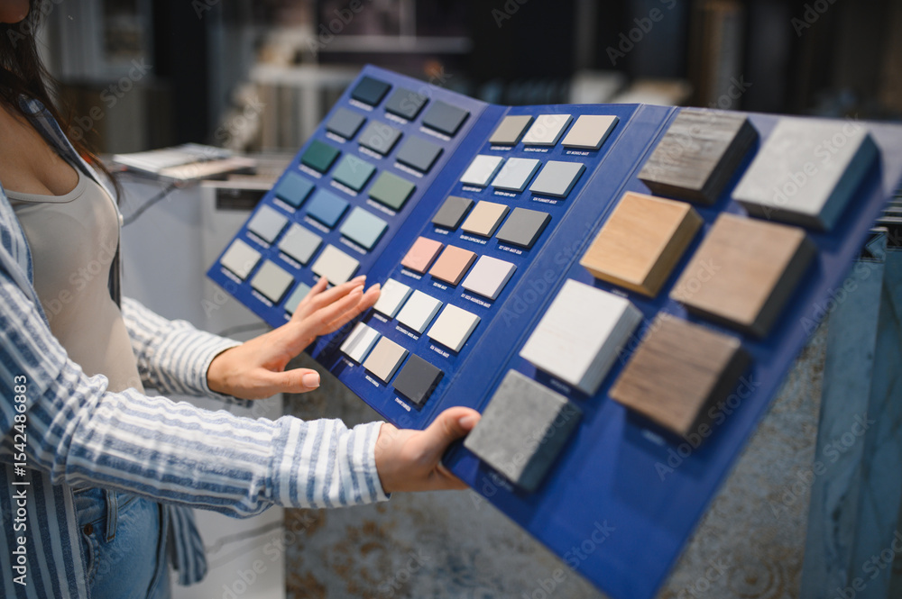 Obraz premium Woman choosing tiles in ceramic and furniture modern shop for her house