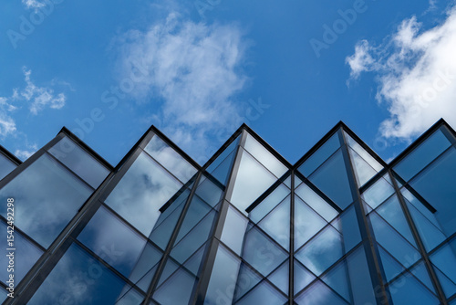 Modern glass building with sky and clouds reflection, abstract urban architecture detail