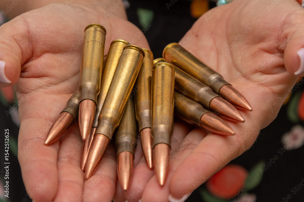 Fototapeta premium A woman's palms with firearm cartridges is a symbol of threat, military conflict or hunting.