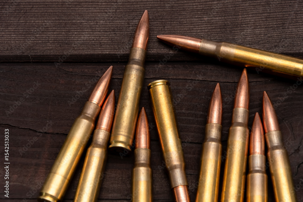 Obraz premium Close-up of various calibres of ammunition lying on a rough wooden board. Suitable for topics related to hunting, shooting or military affairs.