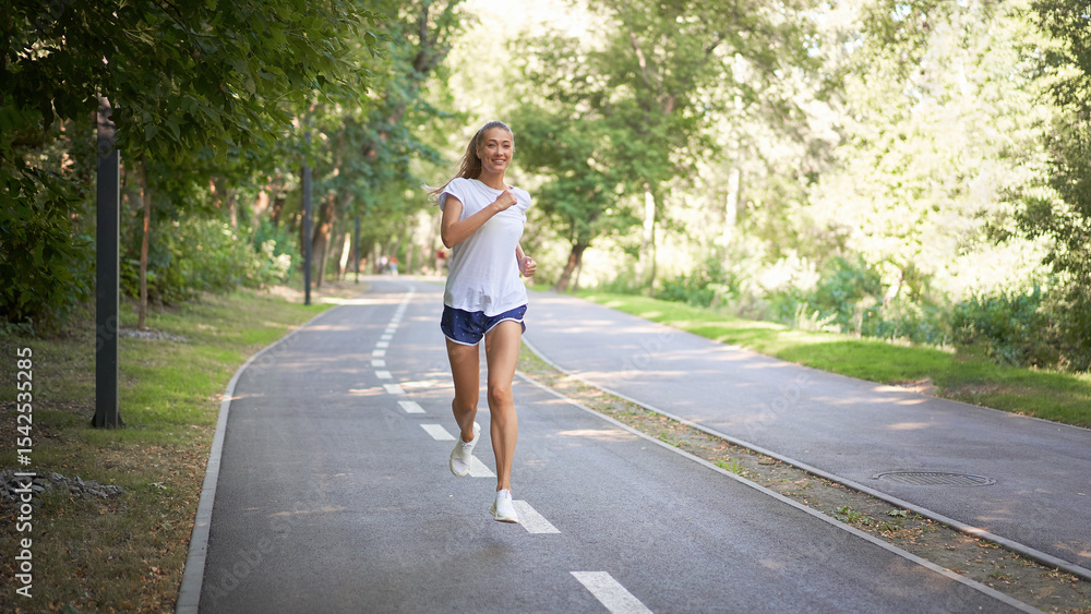 Woman running asphalt road summer park Active sporty caucasian female morning workout Healthy lifestyle concept. Athletic person sportswear exercises Dressed white t-shirt full length Woman running asphalt road summer park Active sporty caucasian female morning workout Healthy lifestyle concept. Athletic person sportswear exercises Dressed white t-shirt full length