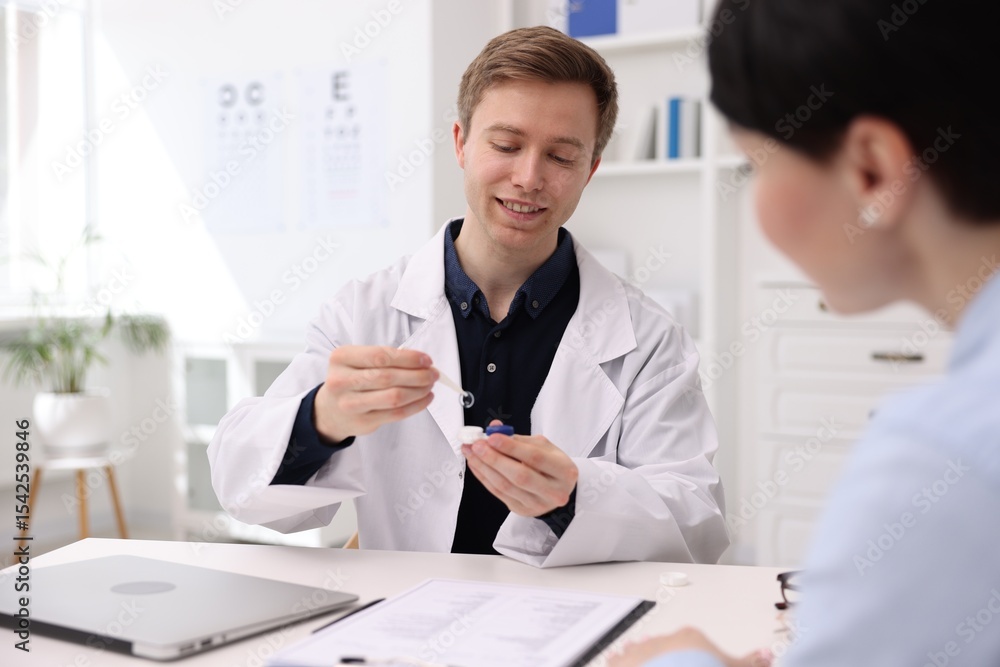 Ophthalmologist consulting woman at white table in clinic Ophthalmologist consulting woman at white table in clinic