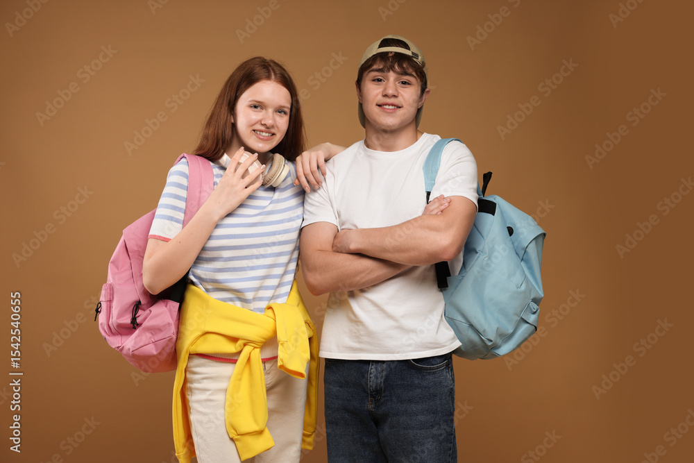 Obraz premium Teenage girl and boy with backpacks on brown background