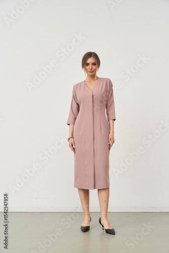Elegant woman in fashionable dress posing in a studio setting with minimalist background