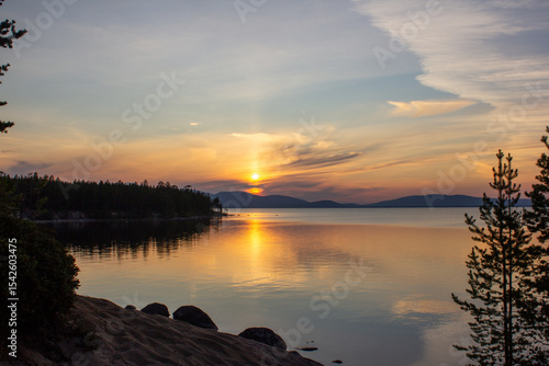  Stunning sunset over a calm lake with golden reflections, mountains on the horizon, and forest silhouette. Perfect for travel, nature backgrounds, peaceful landscapes, eco tourism, and inspiration.