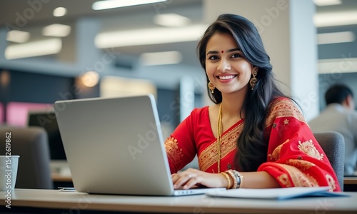 Smiling indian woman working on laptop at office desk