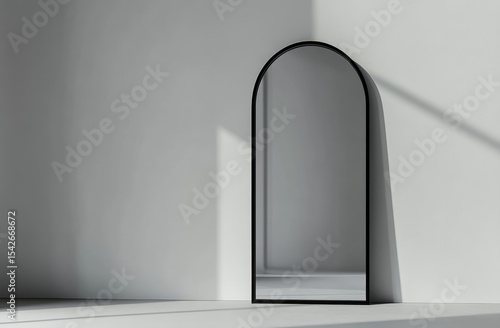 Arch mirror in a minimalist white room. Sunlight casts shadows