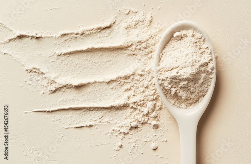 Light beige powder in a spoon, scattered on a surface