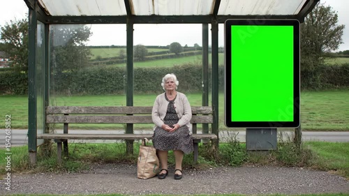 Green screen billboard on rural bus stop with seated elderly person