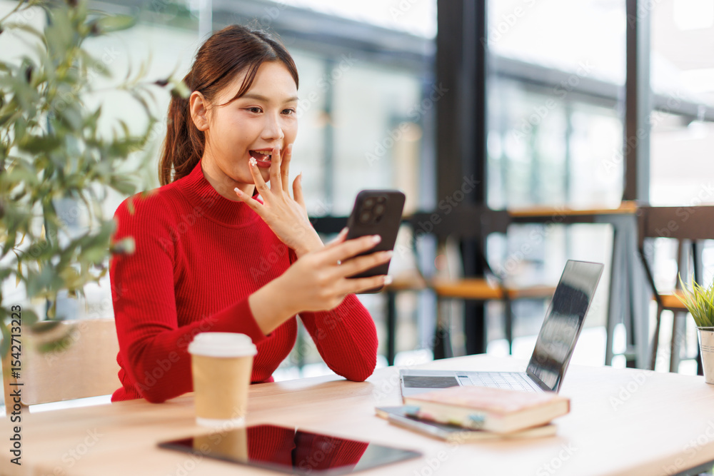 Obraz premium Smiling and happy millennial Asian business young woman chatting with her friends on her phone while relaxing in the office. 