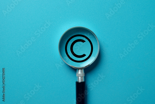 Concept of a copyright audit. A magnifier examines the copyright logo on blue background symbolizing aintellectual property (IP) rights,copyright law.