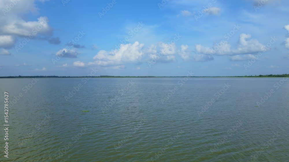 Calm Water Surface Under Blue Sky with Fluffy White Clouds Calm Water Surface Under Blue Sky with Fluffy White Clouds