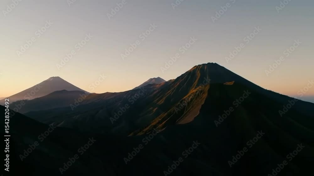 Sunrise over a chain of volcanic peaks, casting long shadows across the ash-covered land below.
Sunrise over a chain of volcanic peaks, casting long shadows across the ash-covered land below.