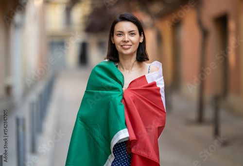 Obraz na plátně Young woman in summer dress wrapped in Italian flag on city street