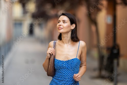 Photography Young woman in dress looking around city street on summer day