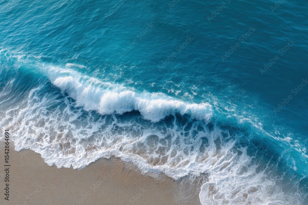 Fototapeta premium A wave crashes on a sandy beach creating white foam and blue water
