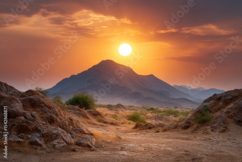 Desert landscape featuring mountains at sunset with a clear sky and rocky foreground