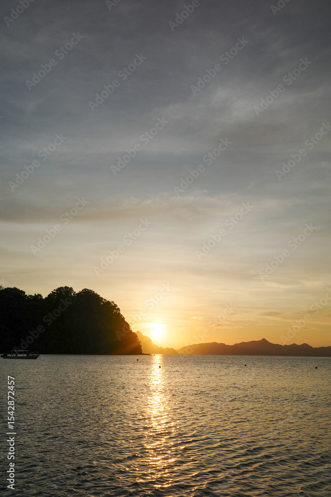 Naklejka premium A beautiful sunset over mountains in Vanilla beach, Coron, Palawan. The last sun ray of the day is the magical moment when the ocean feels warmer. Top tourist attraction in Philippines, Asia