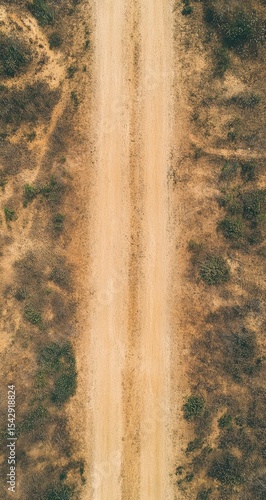 High-angle view of a light beige dirt road winding through a tan landscape