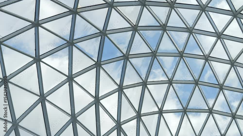 Large, clear dome with a blue sky above it. The dome is made of glass and has a triangular shape Large, clear dome with a blue sky above it. The dome is made of glass and has a triangular shape
