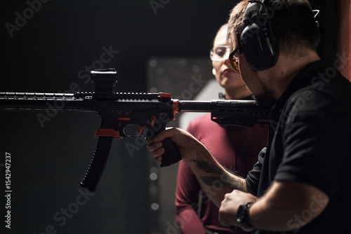 Papier peint Man wearing protective earmuffs instructing Caucasian young woman on holding rif