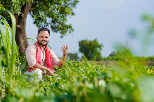young indian farmer working in green agricultural field