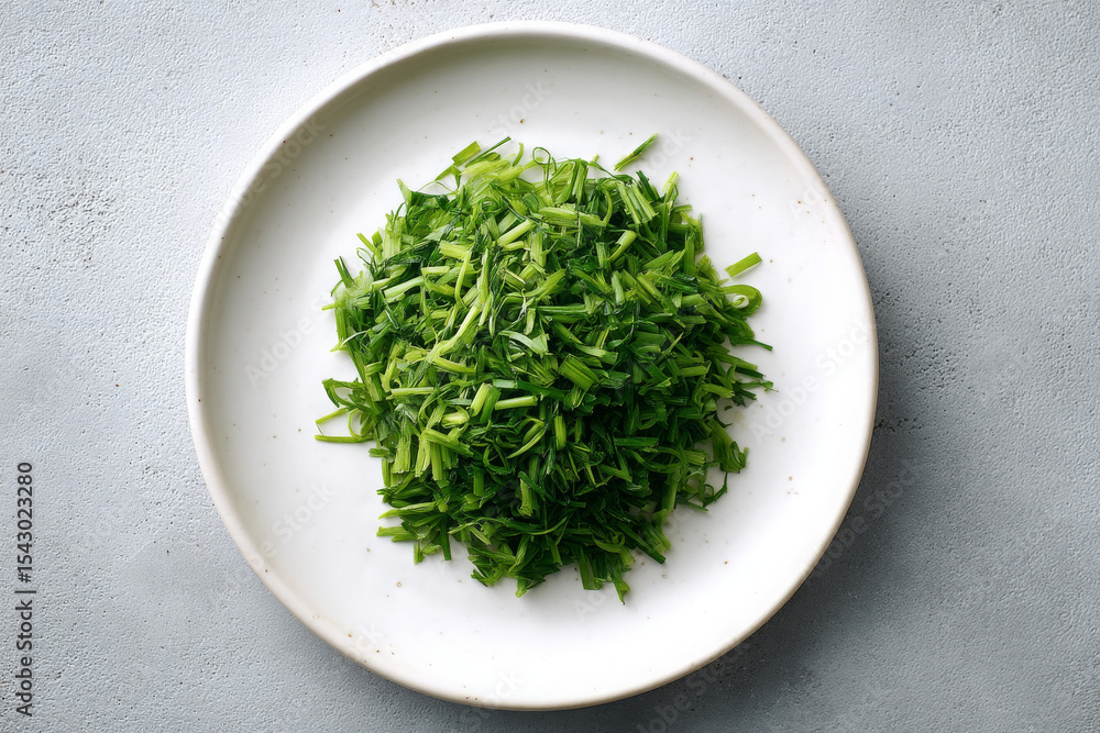Freshly chopped green herbs on white plate, perfect for garnishing dishes Freshly chopped green herbs on white plate, perfect for garnishing dishes