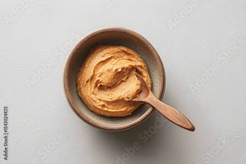 Creamy miso paste in bowl with wooden spoon, perfect for culinary use and flavor enhancement