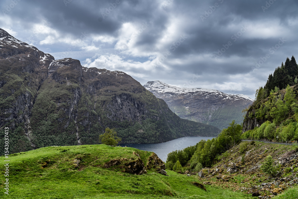 Obraz premium Idyllic Mountainous Fjord Landscape with Lush Forest and Snow-Capped Peaks, Geiranger Fjord, Norway