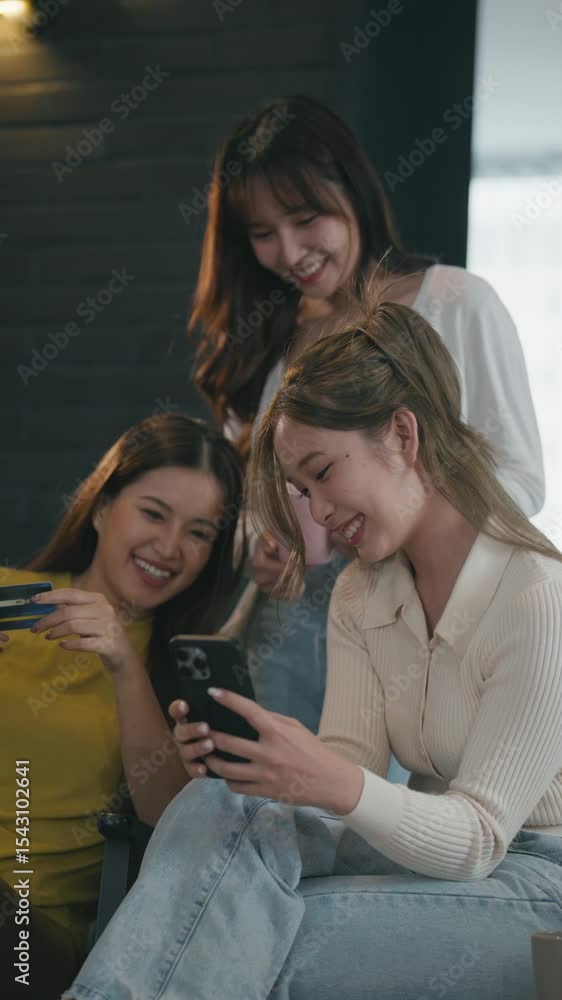 Happy women friends using smartphone for payment at home Happy women friends using smartphone for payment at home