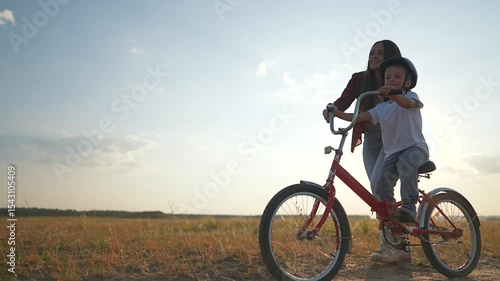 Wallpaper Mural Mother help son learn to ride bicycle at sunset. Scenic moment as mother supports son learning balance bicycle. Emotional family time during sunset son practices riding with mother guidance outdoors. Torontodigital.ca