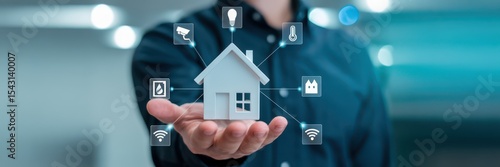 A hand holds a 3d model of a house connected to smart home technology.
