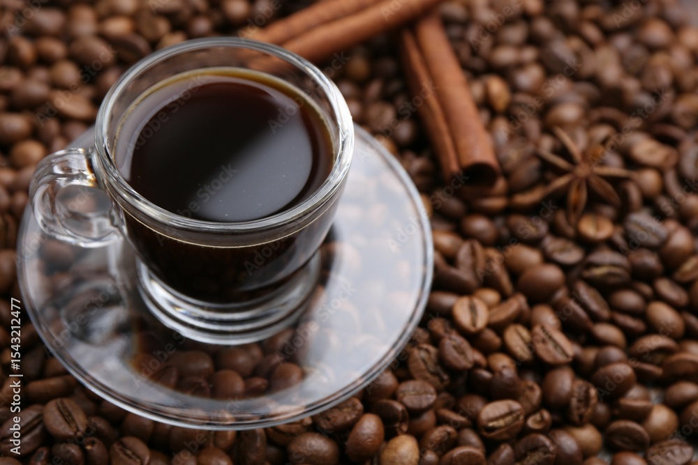 Fototapeta premium Cup with aromatic coffee, star anise and cinnamon on beans, closeup