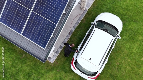 Billede på lærred Electric car being charged at home with solar panel installed on house rooftop