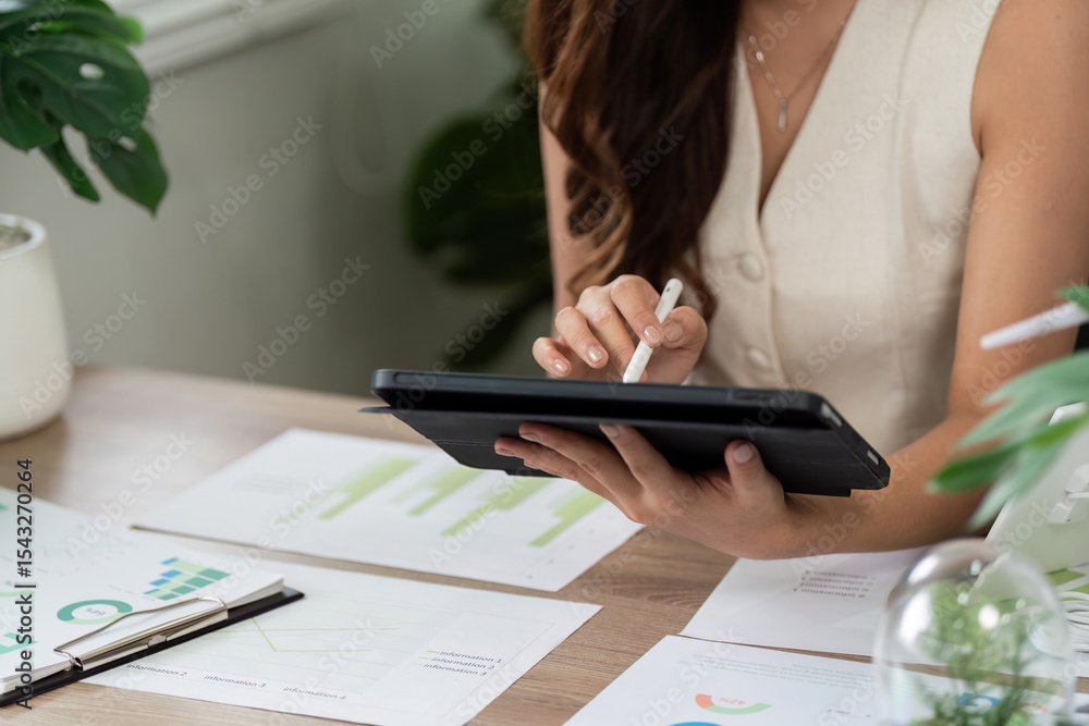 Fototapeta premium Sustainable Business Practices. Professional woman using tablet for ESG analysis in modern office.