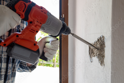 Canvas Print Carpenter electrician with demolition hammer prepares the cavity in the wall where to insert the built-in electrical panel